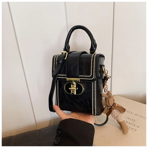 Detail of black crossbody bag with gold studs and cute brown rabbit keychain