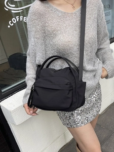 Minimalist black nylon crossbody bag with adjustable strap and multiple zipper pockets