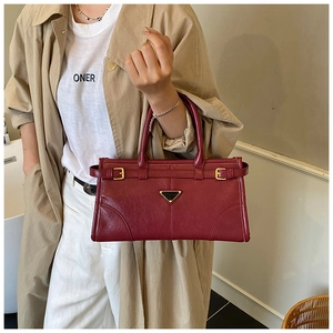 Macro detail of wine red retro textured leather handbag with metallic buckle and twin handles
