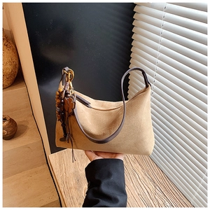 Detail of camel suede hobo bag featuring decorative wooden beads and clover pendant charms