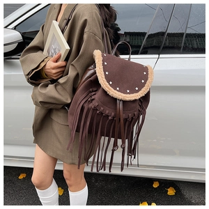 Detail of bohemian brown suede backpack with fringe and metal star studs on a model