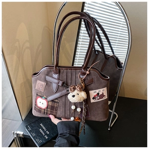 Close-up of brown suede tote bag with cute apple embroidery and plush dog charm