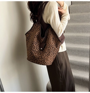 Leopard print tote bag with brown leather trim shown on shoulder in daily commute scene