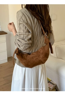Detail of dark brown suede croissant bag with quilted design and knotted shoulder strap