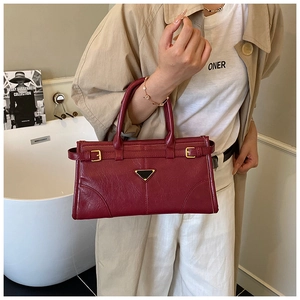 Detailed close-up of a burgundy leather handbag with golden hardware and triangle logo