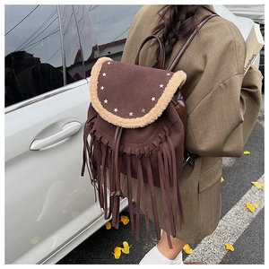 Detail of brown bohemian backpack with star studs, tassels and faux shearling trim