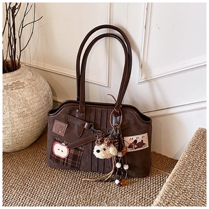 Detail view of vintage brown tote bag with cute apple embroidery and plush dog charm