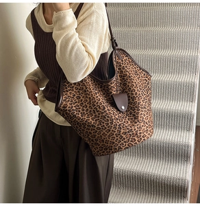 Close-up of leopard print suede tote bag with brown leather trim and metal clasp