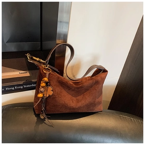 Close-up of brown suede hobo bag with bohemian beaded tassel charm and leather strap