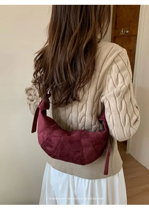Detail view of burgundy matte leather crescent bag in a cozy minimalist autumn setting