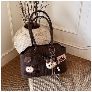 Detailed view of brown suede tote bag with apple embroidery and plush pendant charm
