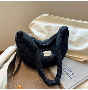Detail of black cloud bag featuring quilted heart patterns and a pearl accented logo