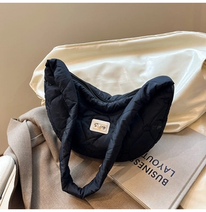 Detail of black heart-quilted puffer hobo bag featuring a white decorative brand plate