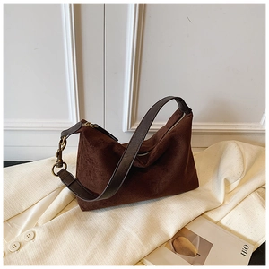 Detail of dark brown suede crescent bag with leather strap and brass hardware on a blazer