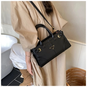 Detail of black leather small square bag with metal logo and adjustable strap