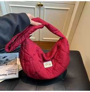 Detail of red crescent quilted bag with heart embroidery and top zipper closure