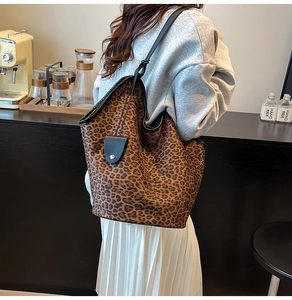 Detail shot of large leopard print suede tote bag with black strap in a cafe setting