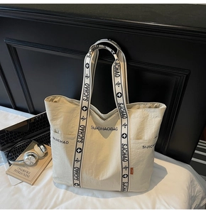 Detailaufnahme der Seitentasche und des breiten Markengurts einer großen Stofftasche