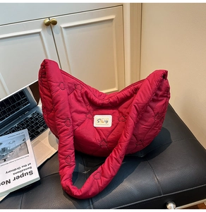 Detail of heart-quilted nylon shoulder bag with pearl-accented logo patch in red