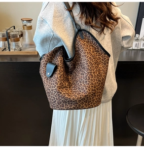 Close-up of leopard print oversized tote bag worn by model in a cozy cafe setting