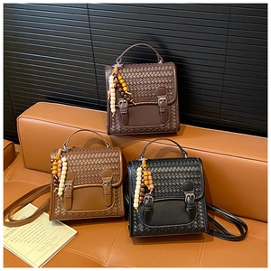Detailed view of three textured woven bags with colorful beaded charms on a leather sofa
