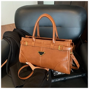 Detail of vintage brown textured handbag with gold hardware on a leather chair