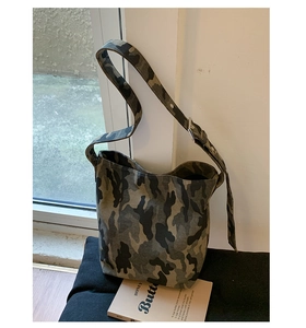 Detail of camouflage canvas shoulder bag with adjustable strap and silver metal buckle