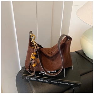 Detail of dark brown suede hobo bag with vintage gold buckle and bohemian wood bead charm