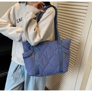 Close-up of quilted blue tote bag with diamond pattern and convenient front zipper pockets