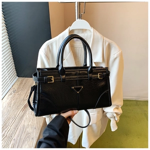 Close-up of the black tote bag featuring a triangle metal logo and gold buckle straps