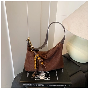 Detail of dark brown suede shoulder bag with retro wooden beads and tassel charms