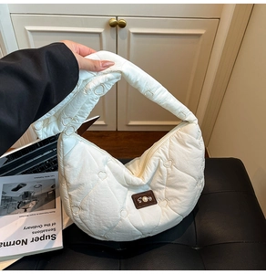 Detailed heart-quilted texture on cream cloud bag with pearl and logo patch detail