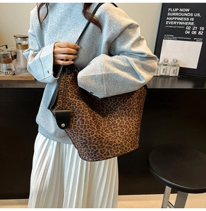 Close-up of leopard print pattern and black leather pendant on a suede bucket bag