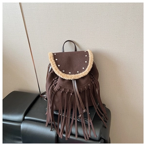 Detail of dark brown suede backpack with fringe, star rivets, and faux fur trim