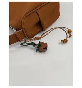 Detailansicht der braunen matten Ledertasche mit handgefertigtem Blumenanhänger und Holzperlen
