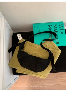 Detail of vintage black suede croissant bag with knot detail on yellow knit background