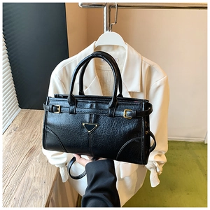 Detail of black textured faux leather handbag featuring a signature triangle metal plaque