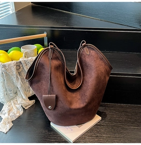 Close-up of brown suede tote bag with leather trim on a wooden display stand