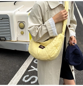 Quilted light yellow hobo bag with heart embroidery and brand patch detail on street