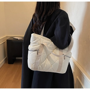 Detail of quilted tote bag with side zipper pocket and wide fabric shoulder strap