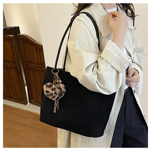 Close-up of a large black tote bag with a trendy leopard print heart plush charm detail
