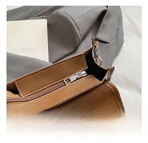 Detail view of smooth dark brown leather texture with silver zipper and fine stitching