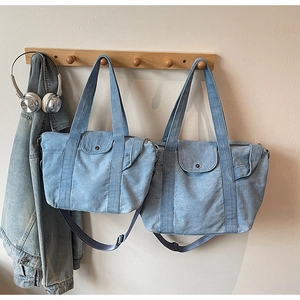 Detail of light blue denim tote bags in two sizes with adjustable straps and front pockets