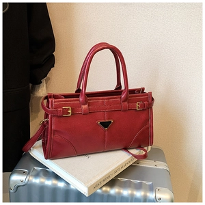 Detail of dark red vintage handbag with glossy texture and iconic triangular metal logo