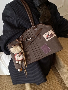 Brown suede tote bag with cute apple embroidery and plush dog charm on a model