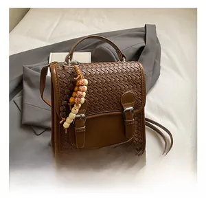 Detail of woven texture flap and metallic buckle on brown faux leather crossbody bag