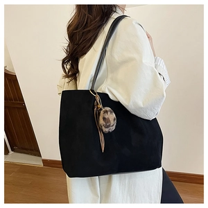 Detail of large black tote bag with leopard print pom-pom and leather tassel decoration