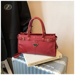 Detail of red leather bag with metal triangle plaque on a silver suitcase