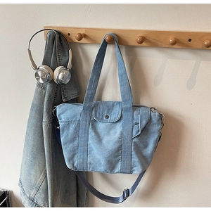 Close-up of light blue washed denim tote bag with adjustable strap and side pocket detail