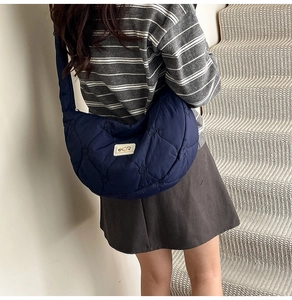 Detail of blue quilted cloud bag with heart stitching and broad strap on a person